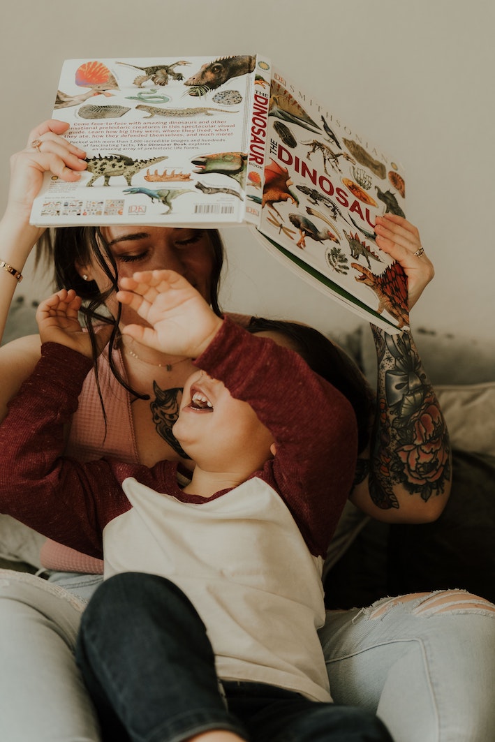 Parents reading a dinosaur book to child